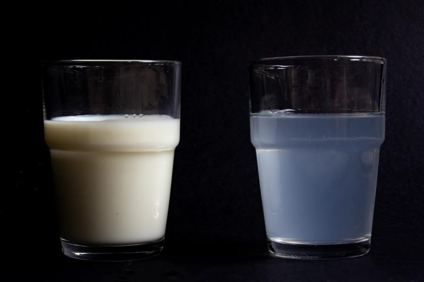 Two glasses showing Rayleigh scattering with water and milk